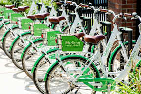 a row of green bikes parked in front of a building