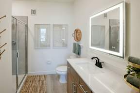 A bathroom with a toilet, sink, mirror, and shower.