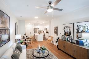 A living room with a white couch, a coffee table, and a ceiling fan.
