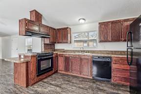 A kitchen with wooden cabinets and black appliances at Country Lane, Cheyenne, Wyoming