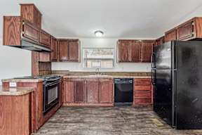 A kitchen with wooden cabinets and black appliances at Country Lane, Cheyenne, Wyoming
