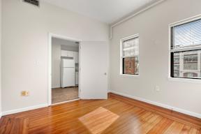 A room with a wooden floor and a white door leading to another room.