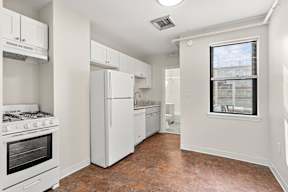 A kitchen with white appliances and a window.