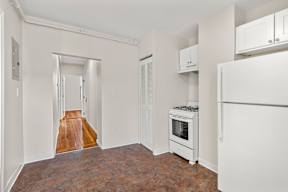 A kitchen with a white refrigerator, oven, and cabinets.