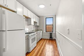 A kitchen with white appliances and wooden floors.