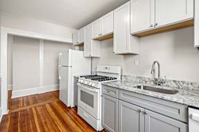 A kitchen with white appliances and wooden floors.