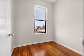 A room with wooden floors and a window showing a street view.