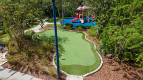 a putting green with a swing in the background
