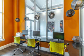 an office with orange walls and a black desk with yellow chairs