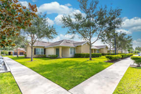 a home at Boca Townhomes with a lawn and trees in front of it