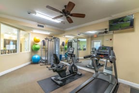 a home gym with cardio equipment and a flat screen tv