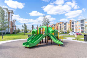 a playground with a green slide in front of an apartment complex