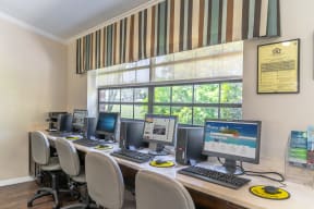 a computer lab with four computers and a row of chairs