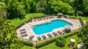 an aerial view of a backyard pool with lounge chairs and a manicured lawn