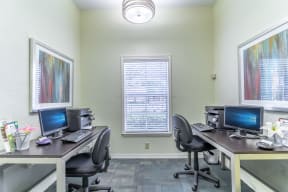 two desks with two computers and two printers in a room with a window