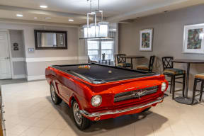 a pool table with a red car in the middle of the room