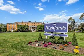 A sign for The Highlands with a building in the background.