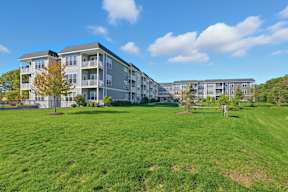 A large grassy area in front of apartment buildings.