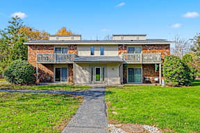A two-story brick house with a balcony and a small front yard.