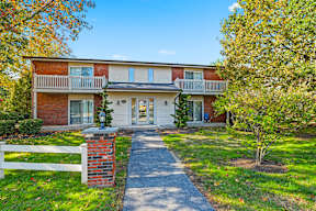 A red brick house with a white fence in front.