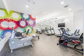A gym with a row of exercise bikes and a television.