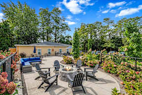 A patio with a fire pit and chairs.