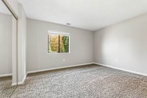 A room with a window and carpeted floor.