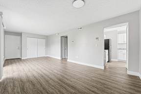 A spacious room with wooden flooring and white walls.
