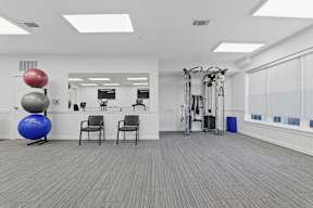 A gym with a blue exercise ball and a row of chairs.