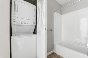 A white washing machine is in a bathroom next to a bathtub.