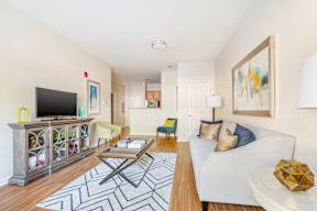A living room with a white couch and a wooden floor.