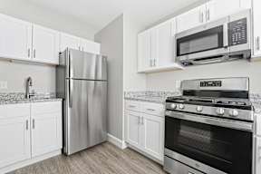 A kitchen with a stainless steel refrigerator, microwave, and oven.
