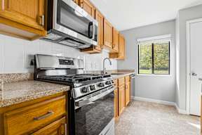 A kitchen with a stove, microwave, and cabinets.