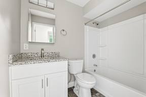 A white bathroom with a marble countertop and a white toilet.