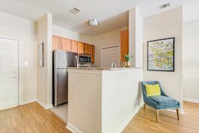 A kitchen with a blue chair and a fridge.