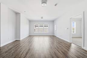 A spacious room with wooden flooring and white walls.