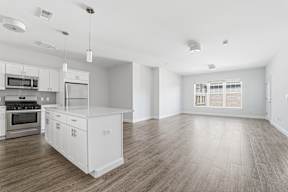 A kitchen with white cabinets and a wooden floor.