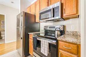 A kitchen with a black refrigerator, black oven, and a black microwave.