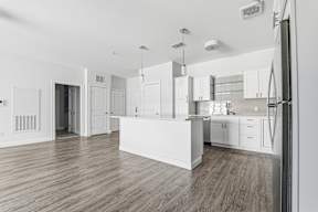 A kitchen with white cabinets and a wooden floor.