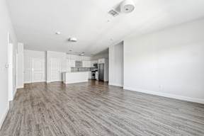 A spacious room with wooden flooring and white walls.