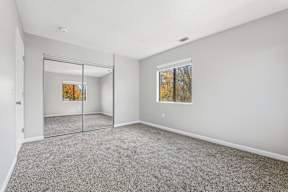 A room with grey carpet and a painting on the wall.