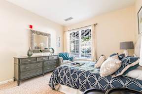 A bedroom with a bed, dresser, and mirror.