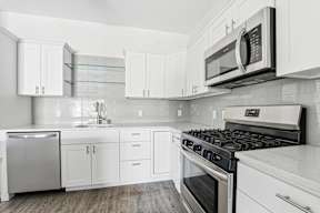 A modern kitchen with white cabinets and stainless steel appliances.