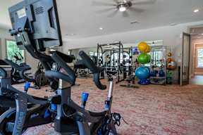 A spin bike is in the foreground of a well equipped gym.