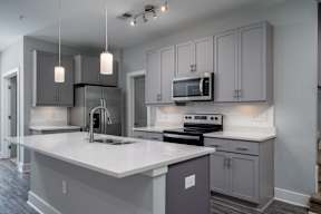 A modern kitchen with a white countertop and grey cabinets.