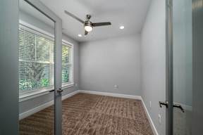 A room with a ceiling fan and carpeted floor.