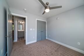 A room with a ceiling fan and carpeted floor.