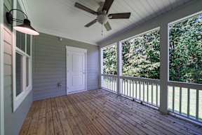 A room with a ceiling fan and a view of trees outside.