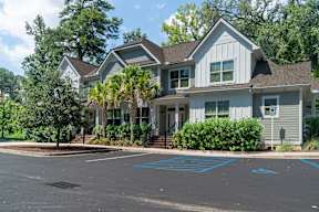 A large house with a grey roof and a driveway in front.