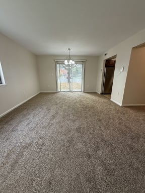 an empty living room with carpet and a door to a balcony